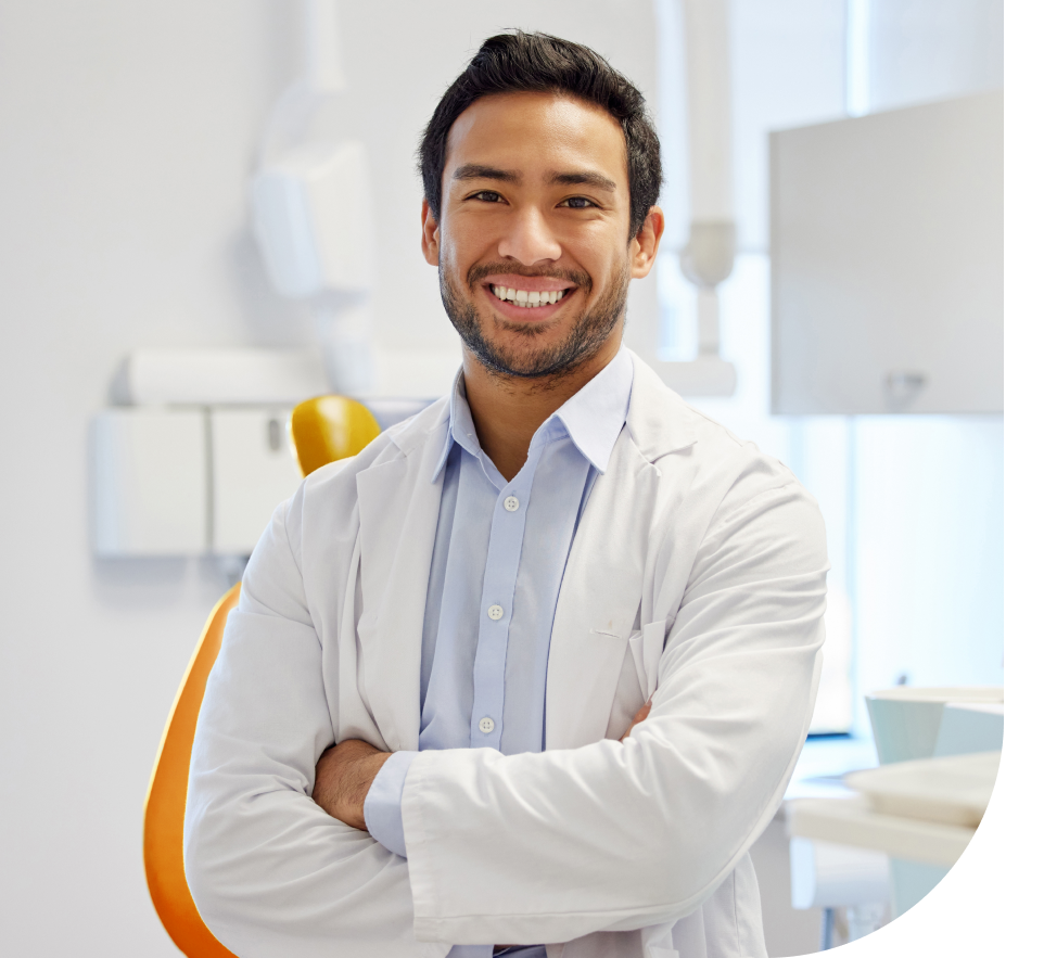 Smiling male dentist in a white coat standing in a dental office