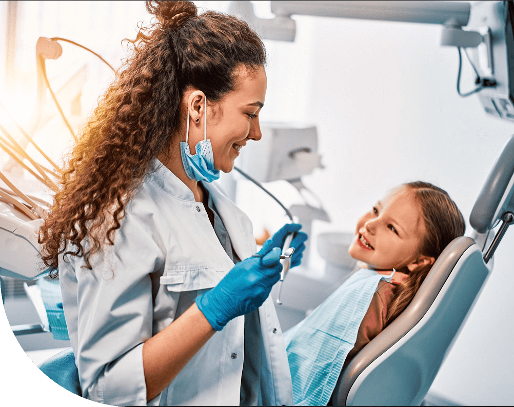 Female dentist smiling and talking to a young girl sitting in a dental chair during a check-up